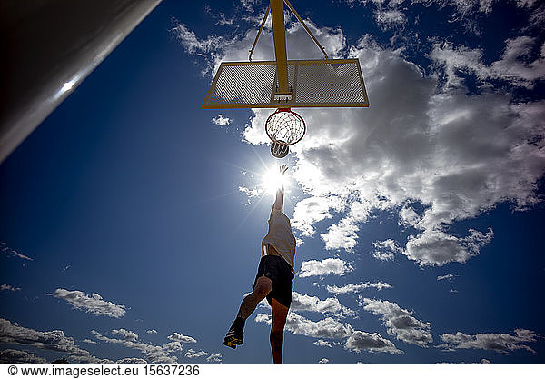 Mann spielt Basketball  dunkelt gegen die Sonne