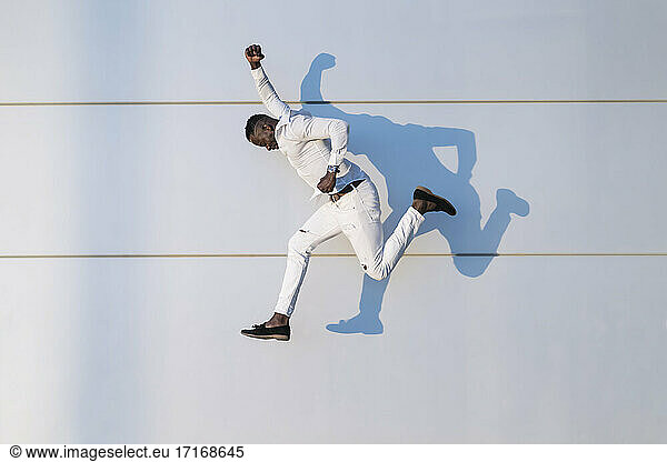 Mann springt durch weiße Wand