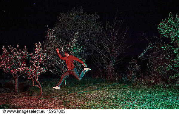 Mann springt nachts im Garten