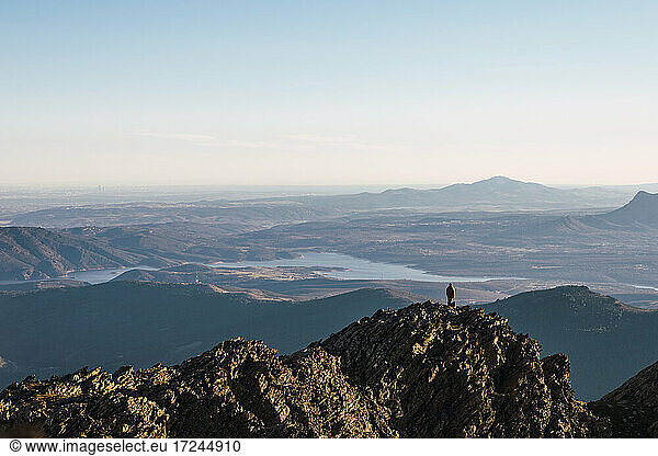 Mann steht im Urlaub auf einem Berggipfel