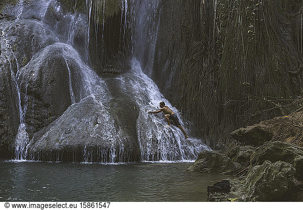 Mann steht unter Wasserfall