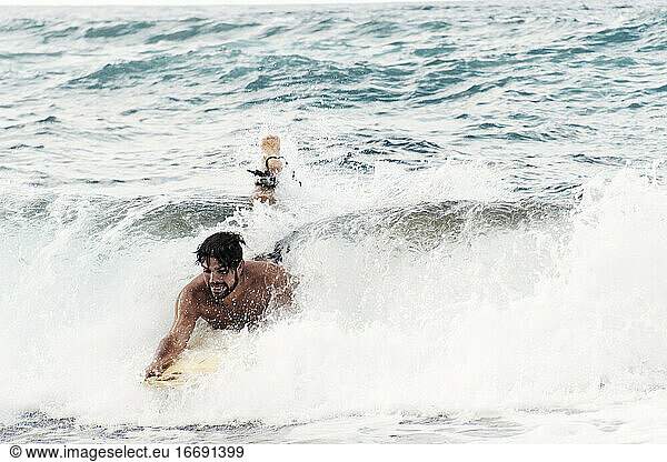 Mann surft mit gelbem Surfbrett