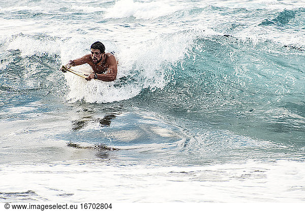 Mann surft mit gelbem Surfbrett
