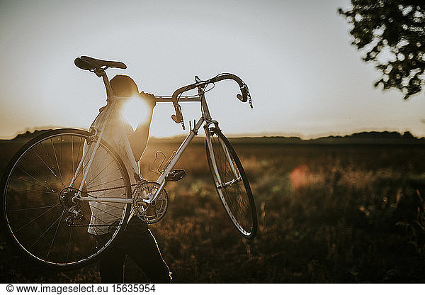 Mann trägt ein Rennrad im Sonnenschein