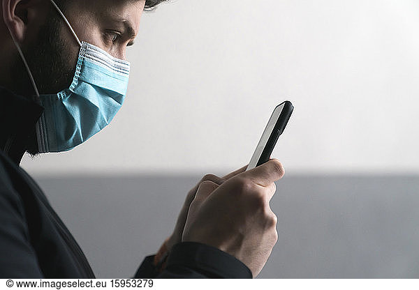 Mann trägt Maske Textnachrichten auf Mobiltelefon