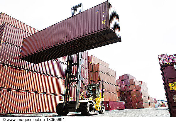 Mann transportiert Frachtcontainer vom Gabelstapler im Handelsdock
