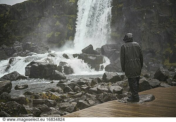 Mann trotzt sintflutartigem Regen und schlechtem Wetter im Nationalpark Thingvellir (Pingvellir)  Goldener Kreis  Island