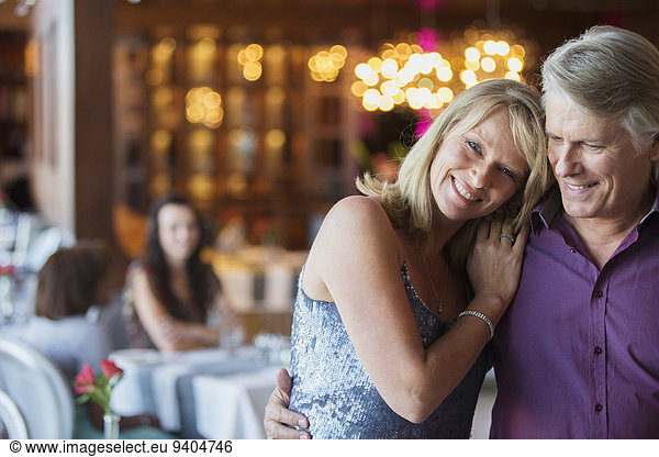 Mann umarmt Frau im Restaurant  Menschen im Hintergrund
