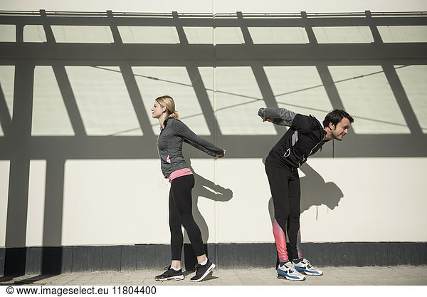 Mann und Frau in Sportkleidung beim Stretching im Freien