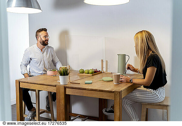Mann und Frau unterhalten sich bei Essen und Trinken am Tisch im Büro