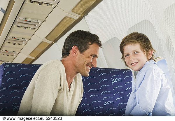Mann und Junge lächeln im Economy-Class-Flugzeug