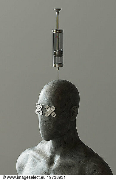 Mannequin with band aid eyes and syringe pierced in head against gray background