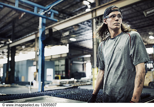 Manual worker looking away while standing in steel factory