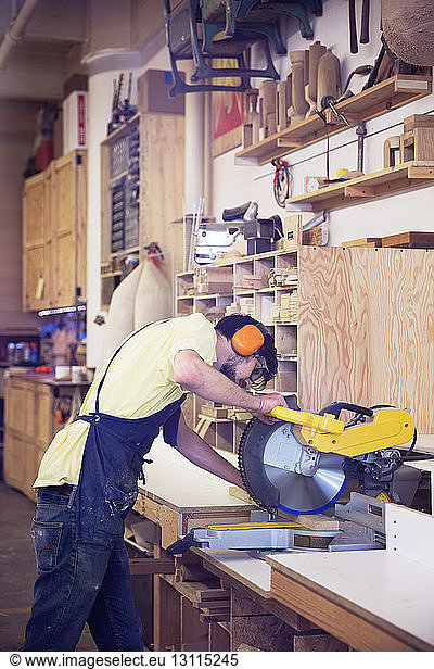 Manual worker using circular saw at wood shop