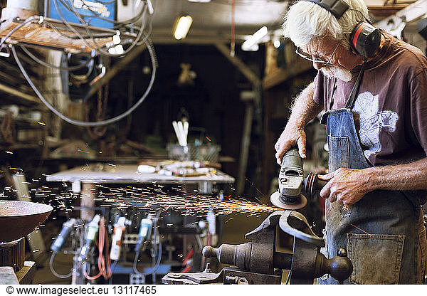 Manual worker using grinder at workshop