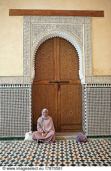 Marokkanische Frau vor einem traditionellen Holztor  Moulay Ismael Mausoleum  Meknès  Marokko  Afrika