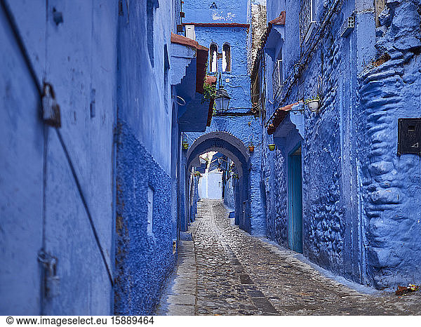 Marokko  Provinz Chefchaouen  Chefchaouen  Torbogen einer leeren Kopfsteinpflastergasse zwischen alten  blau gefärbten Häusern