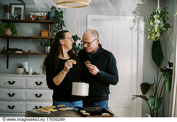married couple tasting fresh baked cookies together in kitchen