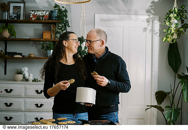 married couple tasting fresh baked cookies together in kitchen
