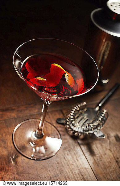 Martini or Manhattan drink with bar utensils on wooden counter