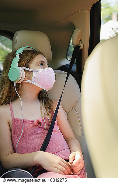 Masked girl (6-7) listening to music in car
