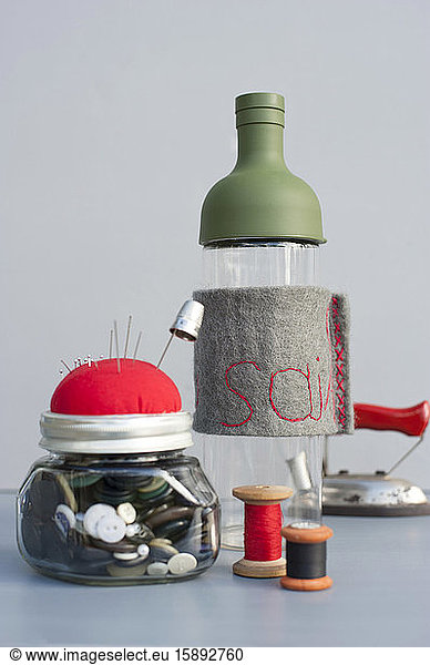 Mason jar with sewing buttons  pin cushion  spools of thread  thimble and bottle with embroidered felt cover