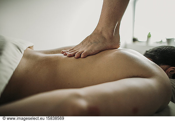Massagetherapeutin verwendet die Ashiatsu-Technik zur Behandlung ihres Patienten