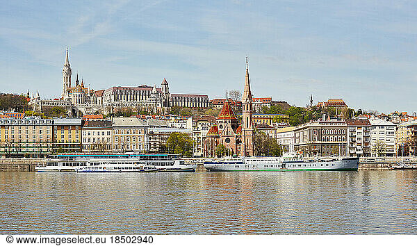 Matthias Church and Reformed church with docked ship on Danube river  Budapest  Hungary