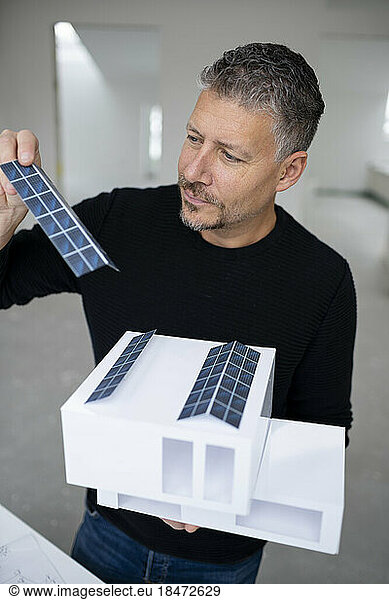 Mature architect examining solar panels of model home