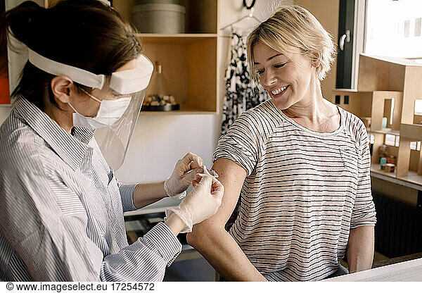 Mature blond woman looking at nurse applying bandage