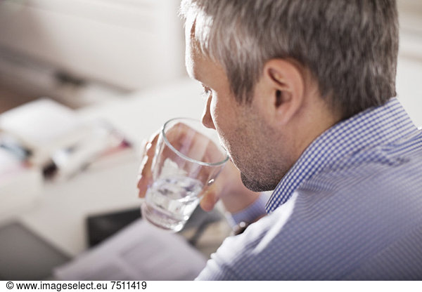 Mature businessman drinking water