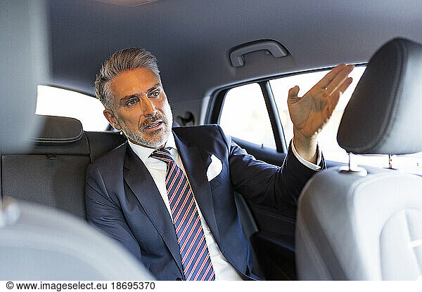 Mature businessman gesturing sitting in car