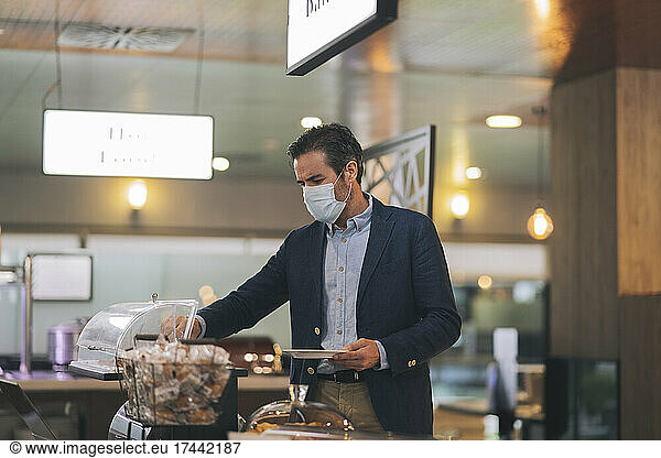 Mature businessman having breakfast in hotel during pandemic