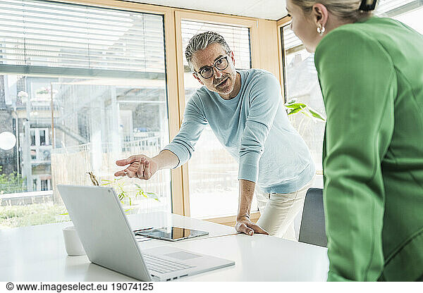 Mature businessman having discussion with businesswoman in office