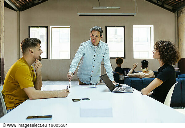 Mature businessman having discussion with colleagues