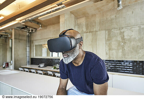 Mature businessman in modern office wearing VR glasses