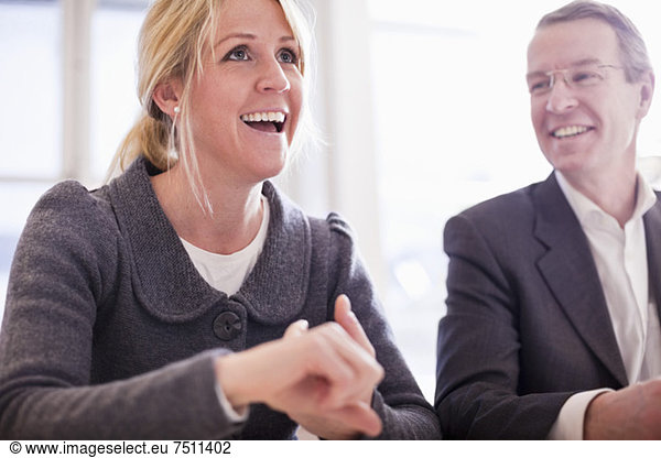 Mature businessman looking at happy female colleague