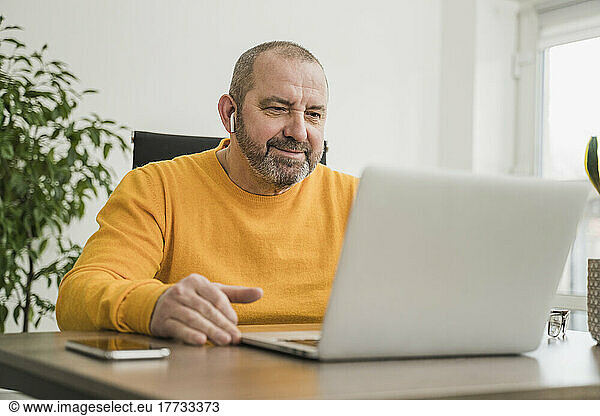 Mature businessman on video call over laptop at work place