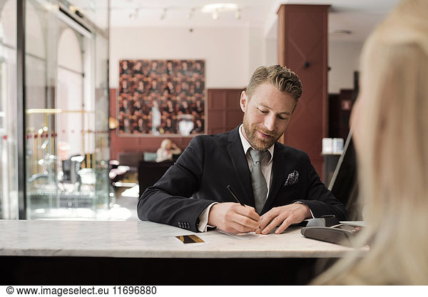 Mature businessman paying through credit card at hotel reception