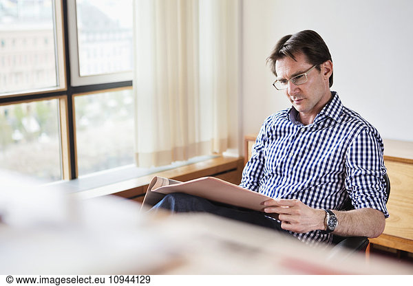 Mature businessman reading document in office