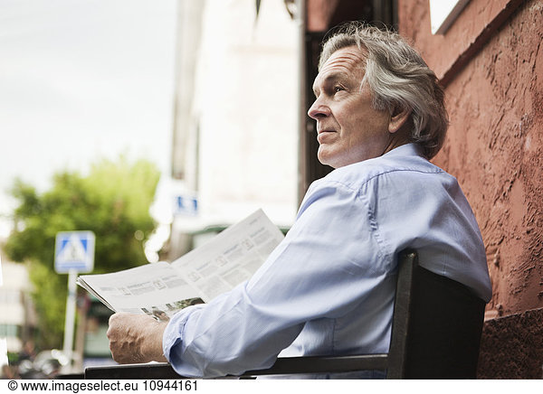 Mature businessman reading newspaper outdoors