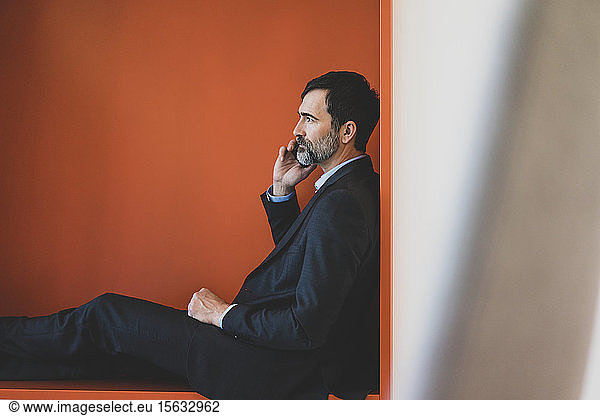 Mature businessman sitting in a niche talking on cell phone