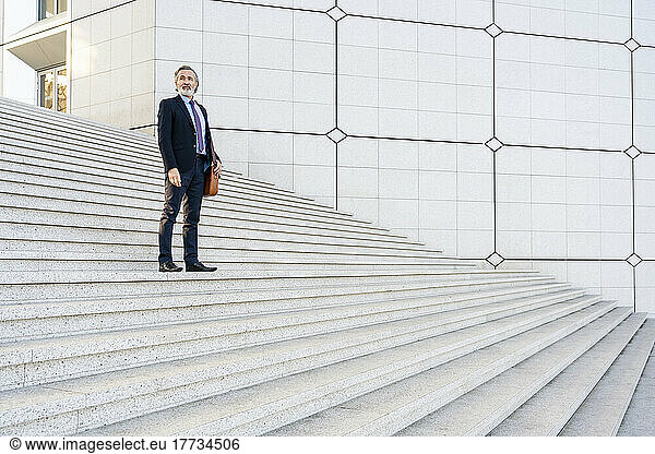 Mature businessman standing on staircase
