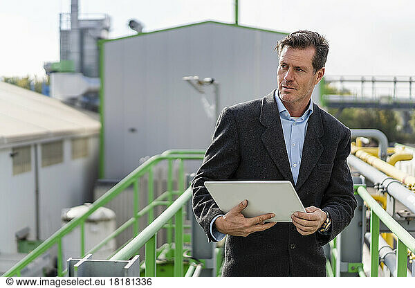 Mature businessman standing with tablet PC