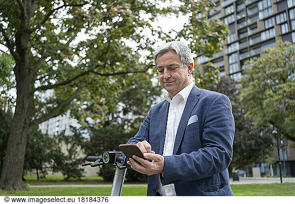 Mature businessman unlocking electric push scooter through smart phone