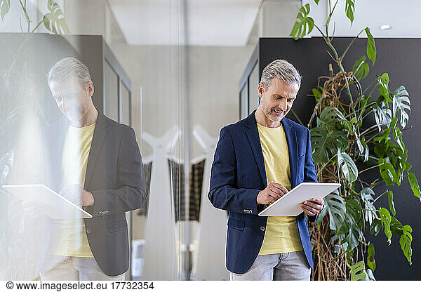 Mature businessman using digital tablet in office