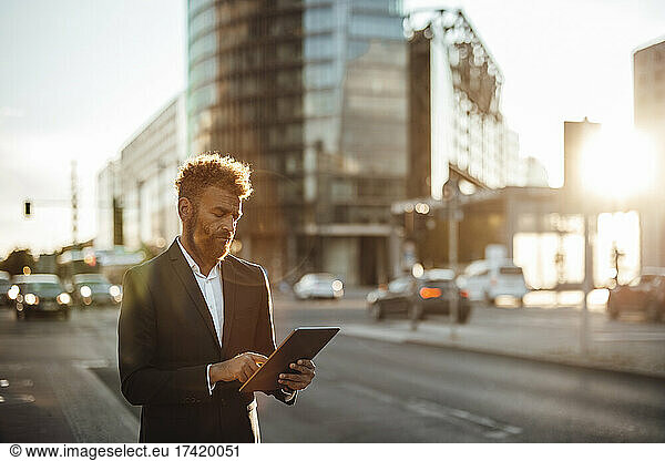 Mature businessman using digital tablet on street
