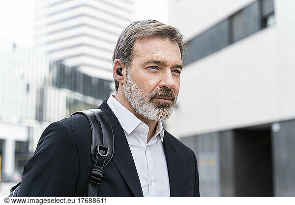 Mature businessman wearing wireless in-ear headphones