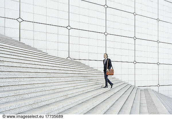 Mature businessman with bag moving up on steps