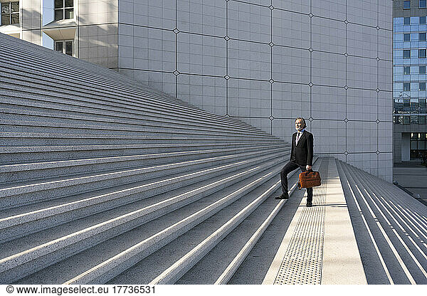 Mature businessman with bag standing on staircase